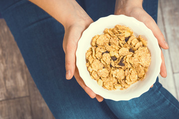 The girl is holding a plate of cereal with fruit. Healthy eating concept. Proper nutrition. Healthy food. Toned image.