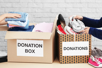 Female volunteers collecting clothes and shoes into donation boxes indoors