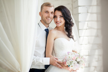 Portrait of the bride and groom. A loving embrace of a wedding couple in a white room