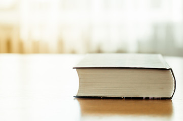 Closed book is lying on a wooden table