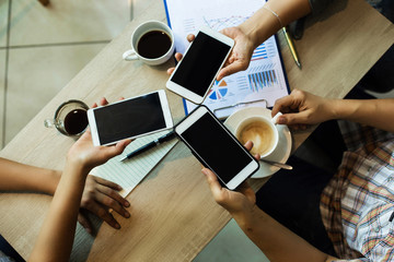 The human hands are using mobile touch together,business team work with mobile phone and business investment paper chart at coffee shop,
