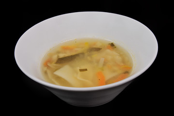 Noodle soup with vegetables on a black
