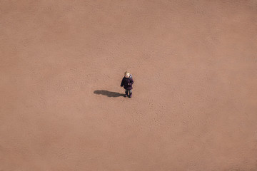 Fototapeta premium small child is standing in the middle of a sandy desert, a conceptual background.
