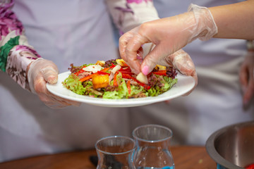 chef decorates the salad with greens