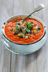 Spicy Mexican roast chicken and tomato soup with black beans,  garnished with fresh avocado