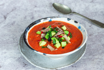 Spicy Mexican roast chicken and tomato soup with black beans,  garnished with fresh avocado