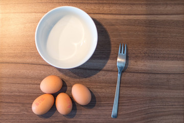 Four eggs a fork and a bowl on a wooden table from above