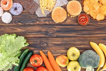 top view of fresh fruits with vegetables and assorted unhealthy food on wooden table