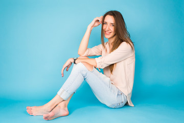 Hipster girl sitting on floor against blue background