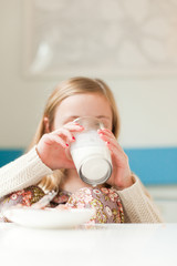 Child drinking milk in white room