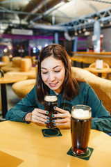 Woman drinking dark fresh beer from a glass in pub