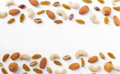 Dried fruits and various of nuts on white background, such as figs, almonds, raisins, cashews, and pistachio.