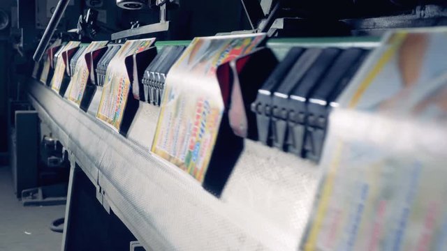 Colourful paper covers are being transported by a industrial machine