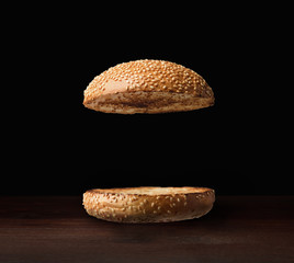 two halves of burger grilled on the grill inside on a black background - obrazy, fototapety, plakaty