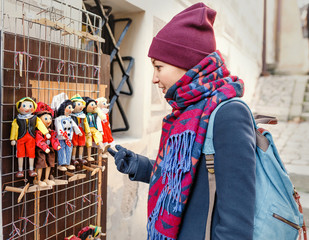 Woman customer looking at traditional puppets made of wood at the souvenir market