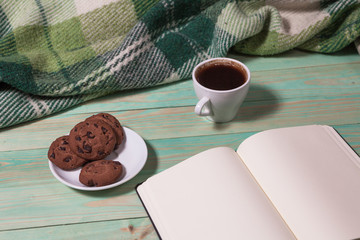 Cup with Hot Tea or Coffee, Warm Plaid, Book on a Wooden Table. with copy space