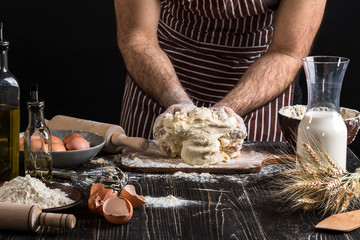 Against the background of men's hands knead the dough. Ingredients for cooking flour products or dough bread, muffins, pie, pizza dough .