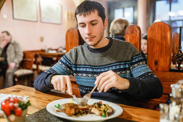 Handsome man eating christmas czech cuisine grilled or fried carp fish in restaurant