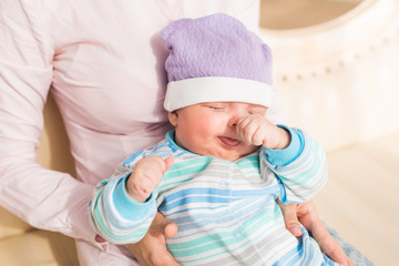 Mother holding her sleeping baby son in the room