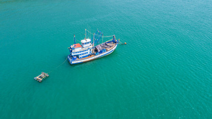 Fishing boat floating in the sea. The beautiful bright blue water in a clear day.Aerial view.Top view.