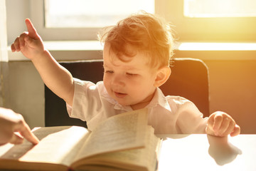 The little boy reads a book. Early learning of child