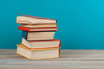 Book stacking. Open hardback books on wooden table and blue background. Back to school. Copy space for ad text