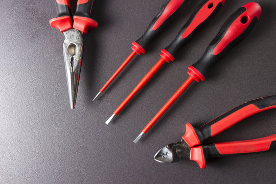 Tools electrician screwdrivers, pliers, platypuses on a black background.