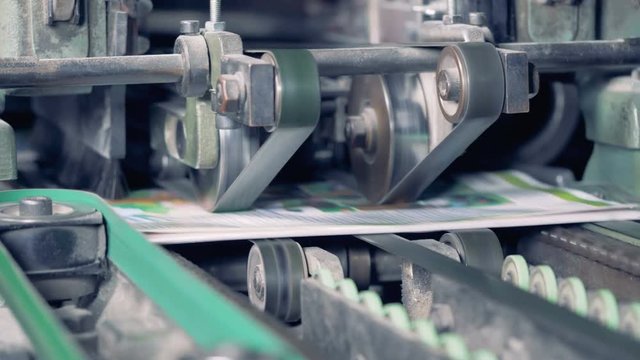 Close up of a factory cutting machine shearing sides of newspapers
