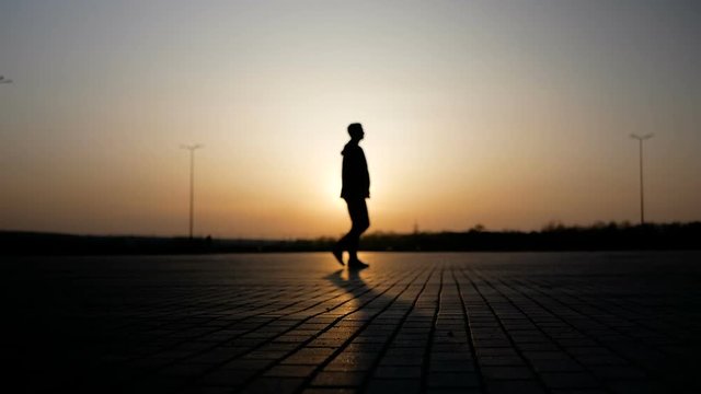 The girl is driving by on the segway against the backdrop of the sunset, and a young man is walking by her.
