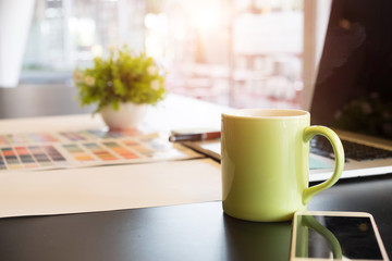 Cup of coffee on creative workplace with green mug a coffee break and coffee time concept.
