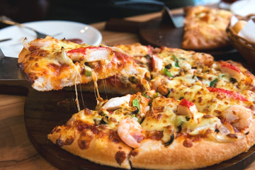 Slice of pizza cheese crust seafood topping sauce. with bell pepper vegetables delicious tasty fast food italian traditional and soft drink carbonated fresh on wooden board table classic.