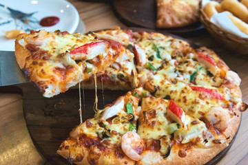 Slice of pizza cheese crust seafood topping sauce. with bell pepper vegetables delicious tasty fast food italian traditional and soft drink carbonated fresh on wooden board table classic.