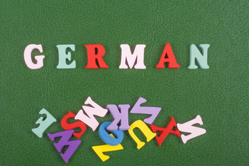 German word on green background composed from colorful abc alphabet block wooden letters, copy space for ad text. Learning english concept.