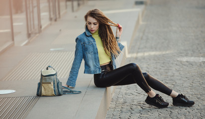 Stylish woman with bag sitting on street