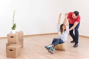 Married couple in new home riding on a cardboard box
