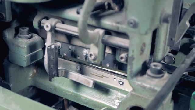 Factory machine is shearing excessive part of coloured newspapers