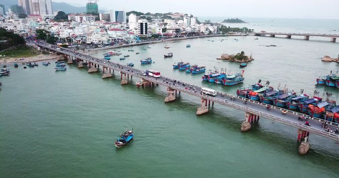 Drone watches for a fishing boat emerges from under the bridge,in the background,on the bridge, traffic of a big sea city Nha Trang,Vietanm