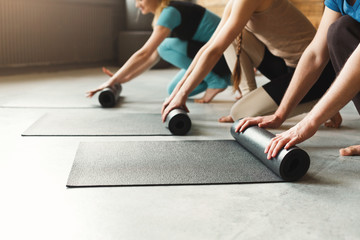 Women and men rolling yoga mat and preparing for training