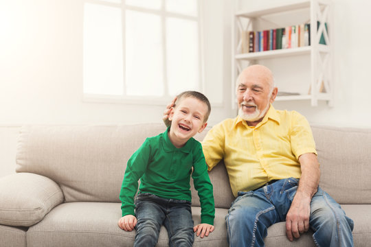 Little boy sitting on couch with his grandfather