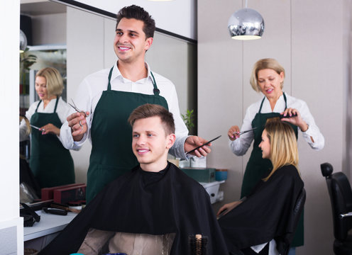 Hairdresser cutting hair of teenage