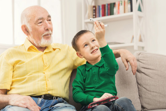 Boy playing with toy pane with his grandfather