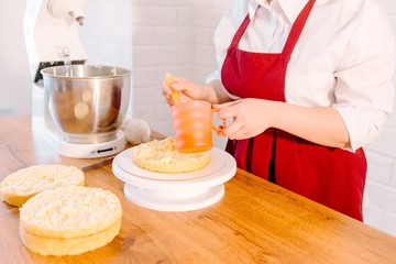 Pastry cook at the table in the kitchen, pours syrup cake