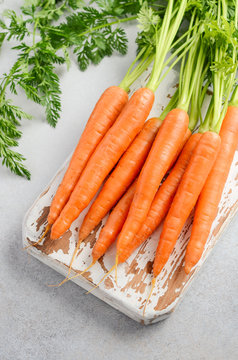 Bunch of fresh carrots on wooden cutting board, selective focus.