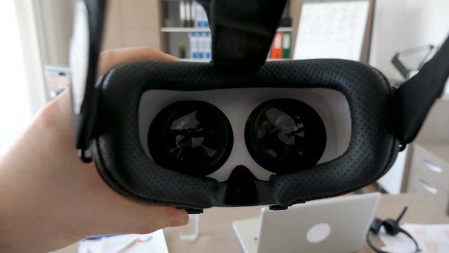 POV shot of putting VR virtual reality headset on then taking it of. Everething takes place in business office