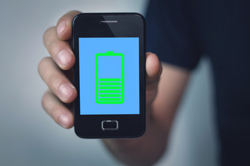 Man showing phone with green battery icon on screen.