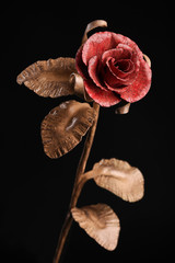 The fine rose made by a forging method of metal with a red blossom and a stalk of light-brown color.