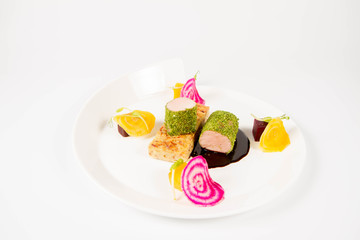 Roast pork tenderloin with crispy potato bread, marinated beetroots and green pepper sauce on a plate on a white background