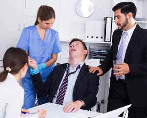 Businessman in fainting receiving first aid in office