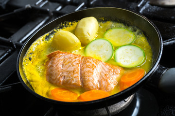 Frying salmon in pan with vegetables in citrus marinade