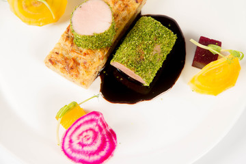 Roast pork tenderloin with crispy potato bread, marinated beetroots and green pepper sauce on a plate on a white background